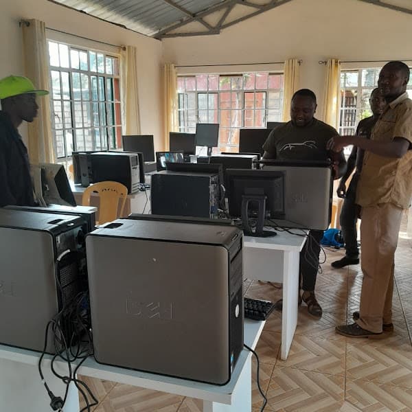 Men setting up a computer lab with Dell desktop towers and monitors on white desks.
